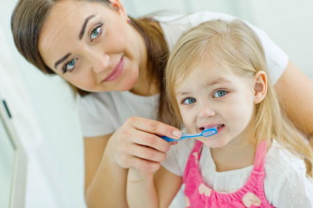 Mom and Daughter brushing their teeth - Pediatric Dentists